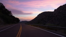 Driving POV on a scenic mountain road at sunset