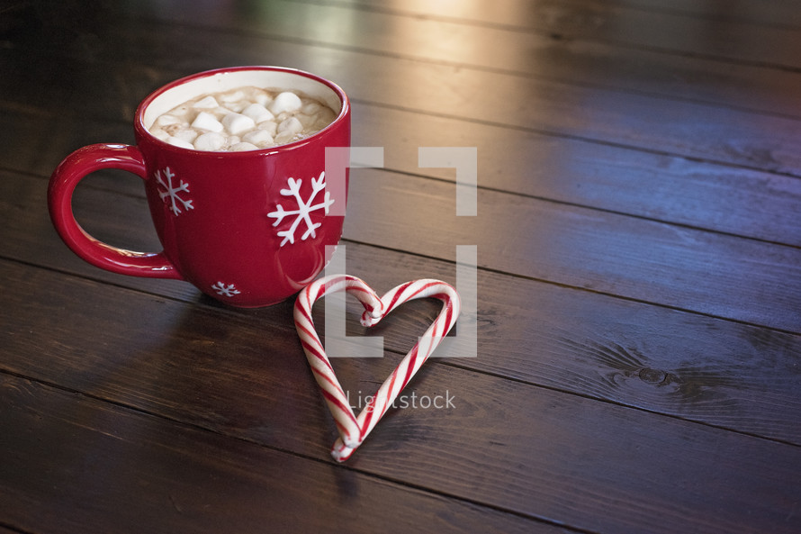 marshmallows and hot cocoa in a red mug and a candy cane 