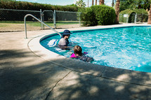 a father and daughter swimming in a pool 
