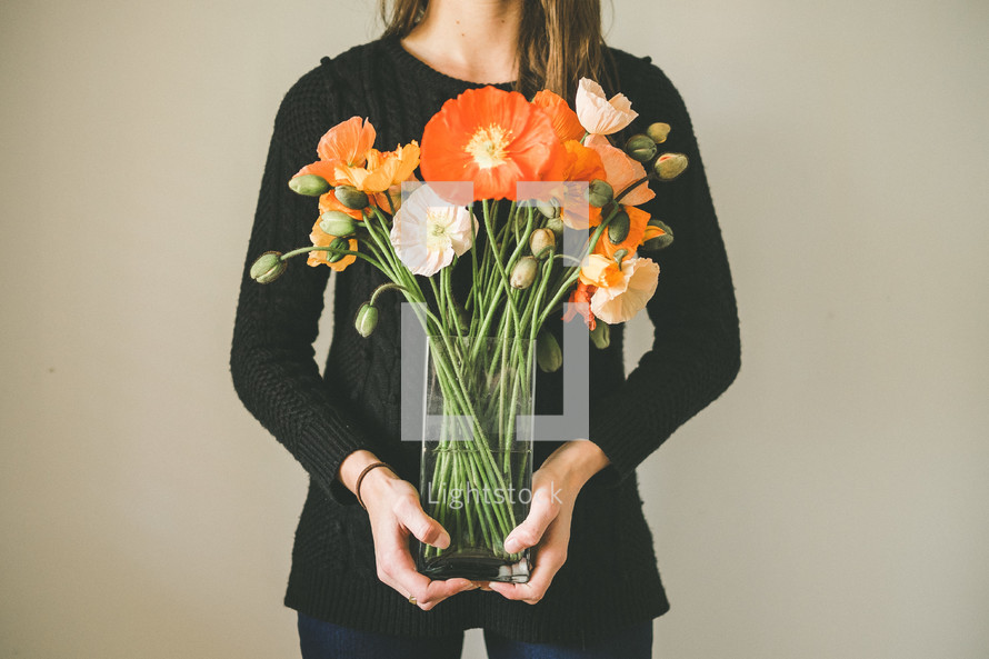 a woman holding a vase of flowers 