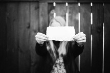 girl holding up a blank piece of paper 