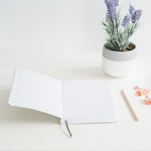 open pages of a journal, potted lavender plant, pencil, and clips on a desk 