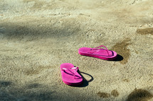 pink flip flops on concrete 