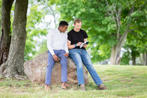Guys sitting on a rock reading the Bible