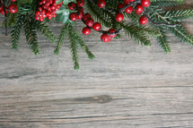 red berries and Christmas greenery on a wood background 
