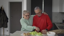 Mature couple dancing while cooking together at home - Mature people having fun preparing the lunch.