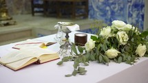 Church altar with flowers, bible and a chalice.