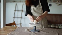 Girl potter forms her product and turns the potter's wheel.