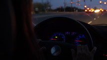 Close up of a woman driving her car at dusk from behind