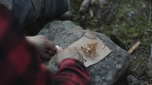 a man lighting a fire with flint in a forest 
