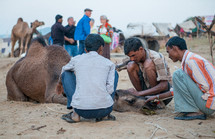 men helping a sick camel in India 