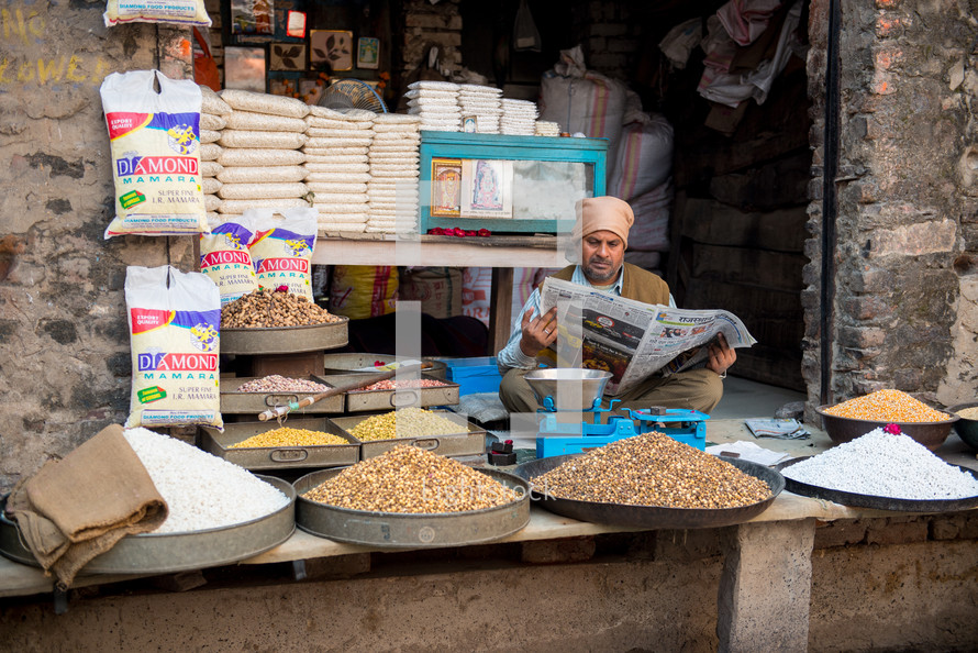 vendor selling spices and grains at a market in India 