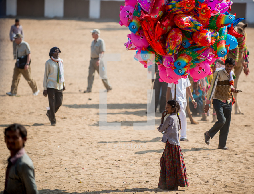 a girl selling balloons at a festival in India 