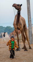 a child leading a camel in India 