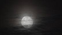 Moon slowly rising with clouds in front of it