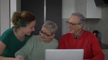 Daughter and senior parents together bonding in front the laptop, slow motion.
