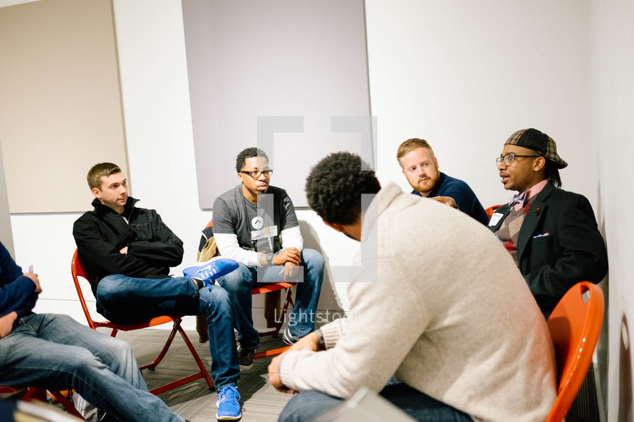 A group of young men sitting in a circle and listening to someone speaking.