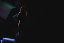 silhouette of a woman singing into a microphone 