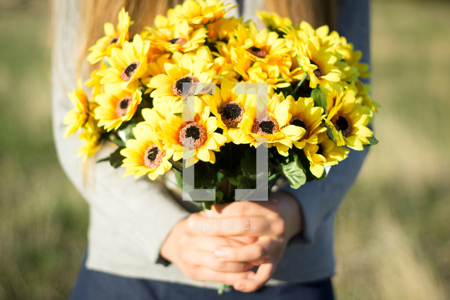 Girl holding bunch of yellow flowers