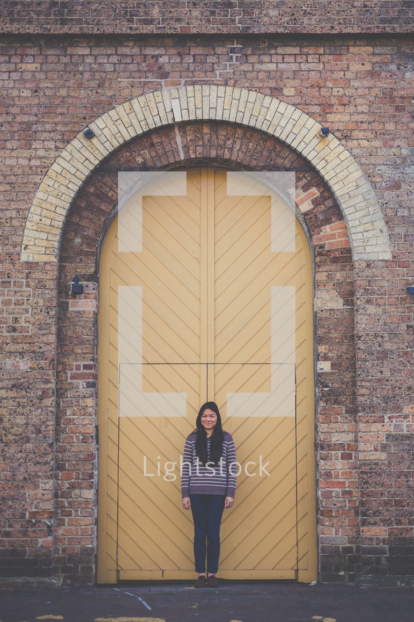 woman leaning against a door to a warehouse 