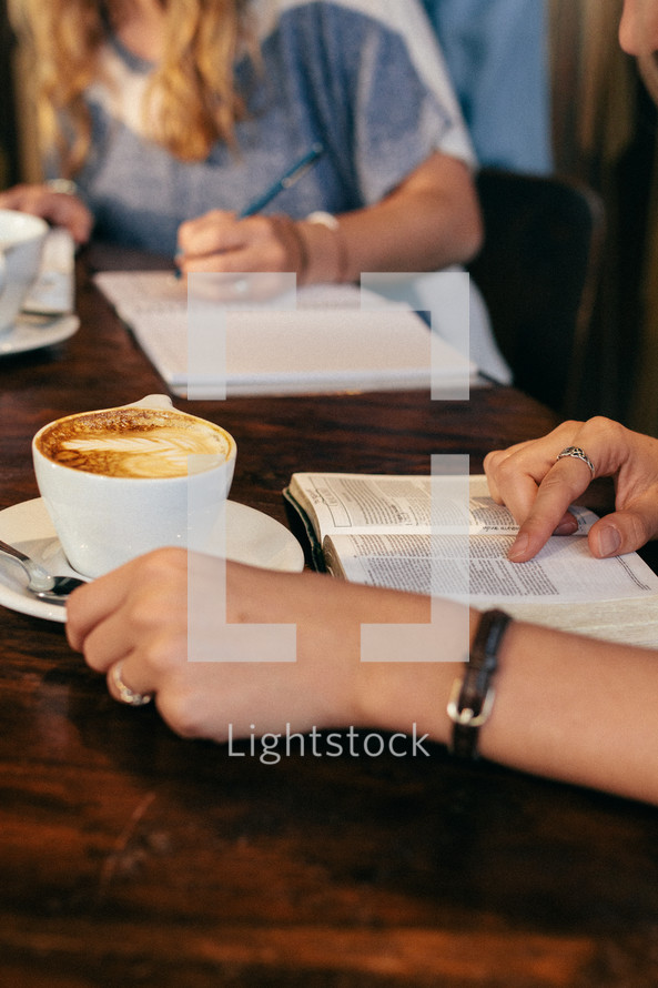 a woman writing in a notebook in a coffee shop at a Bible study 