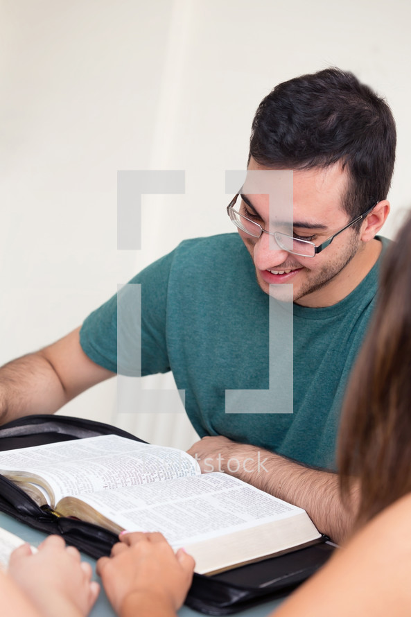 a young man reading a Bible at a Bible study 
