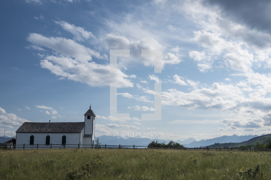Small white country church on a sunny day, mountains in the background