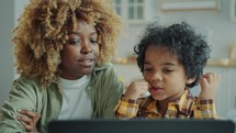 Black Mother and Little Son Watching Educational Video on Laptop at Home
