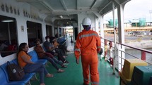 Asian Man working on ship walks past passengers Ferry Workers