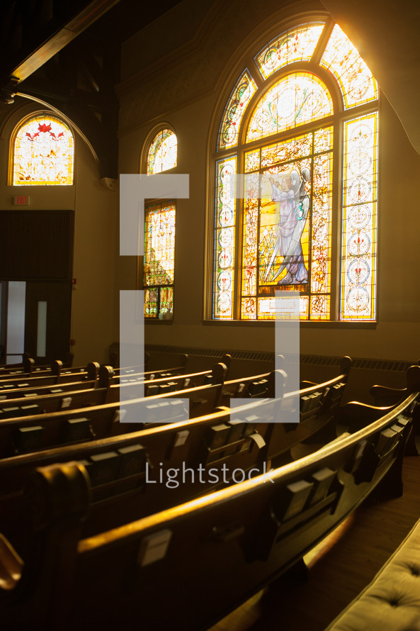 Sunshine through a decorative stained glass window in a church sanctuary.