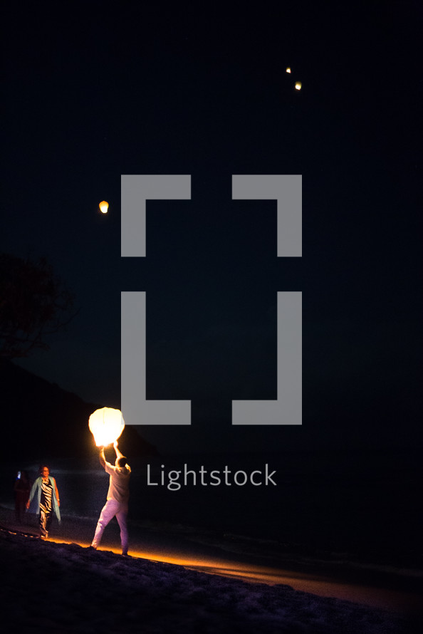 man releasing paper lanterns into the night sky