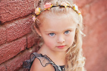 a little girl with a flower headband in her blonde hair 
