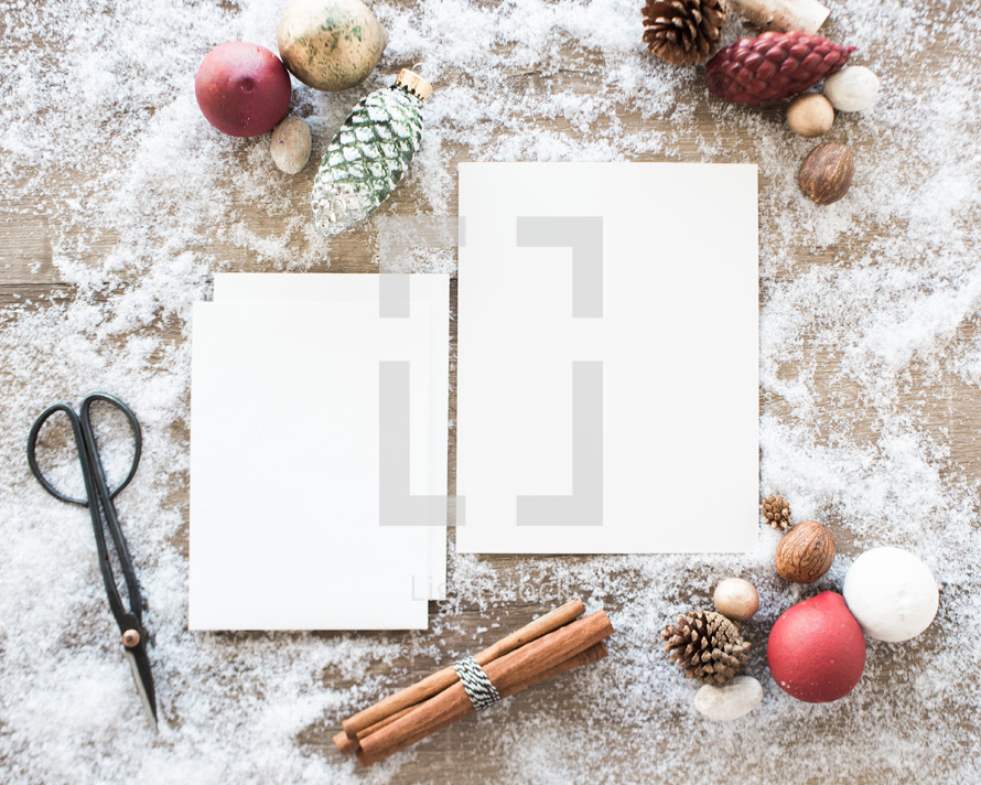 white paper and envelopes with ornaments in snow 