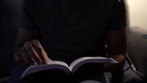 man sitting on a couch reading a Bible for morning devotion 