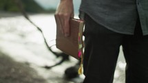 a man walking on a beach carrying a Bible 