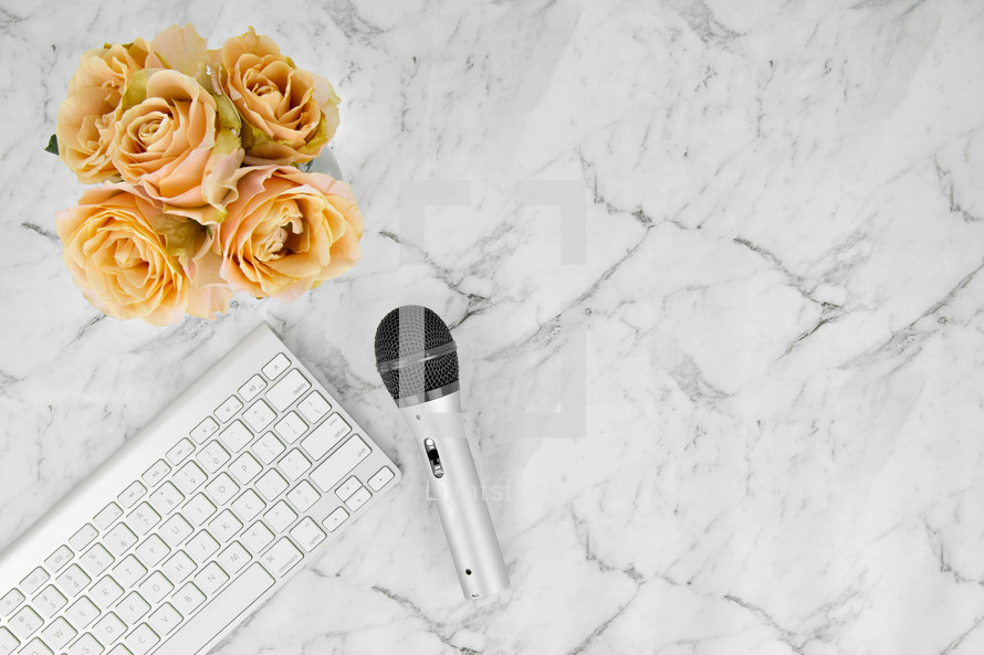 microphone, computer keyboard, and yellow roses on a marbled background 