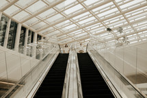 couple standing at the top of an escalator 