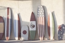boogie boards and surfboards with flags from various nations painting on them 