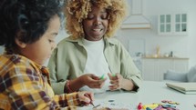 Joyful African AmericanMom and Kid Drawing on Coloring Page Together
