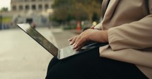 Young business woman walking around the city using her phone and laptop