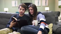 a couple reading a Bible together on a couch 
