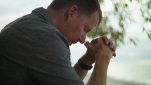 a man sitting on a beach praying 