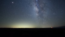 Timelapse of the Milky Way over a vast prairie with a forest fire in the distance