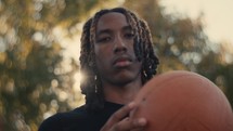 Portrait of a smiling young man playing basketball on a sunny day