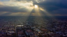 God rays (crepuscular rays) shining on a city in an aerial timelapse.