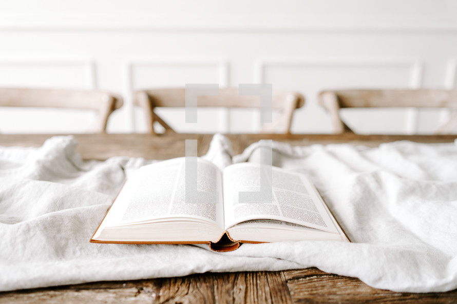 opened Bible on a white blanket on a table 
