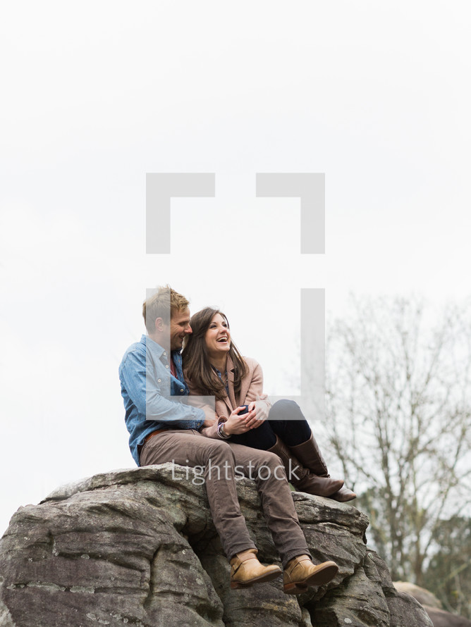 couple hugging sitting on a rock 
