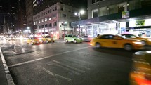 cabs and city buses passing on a city street at night 