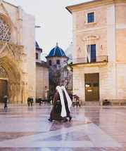nuns walking through a town square 