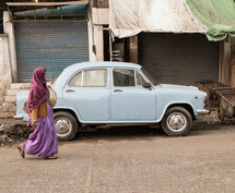 a vailed woman walking past a parked car 